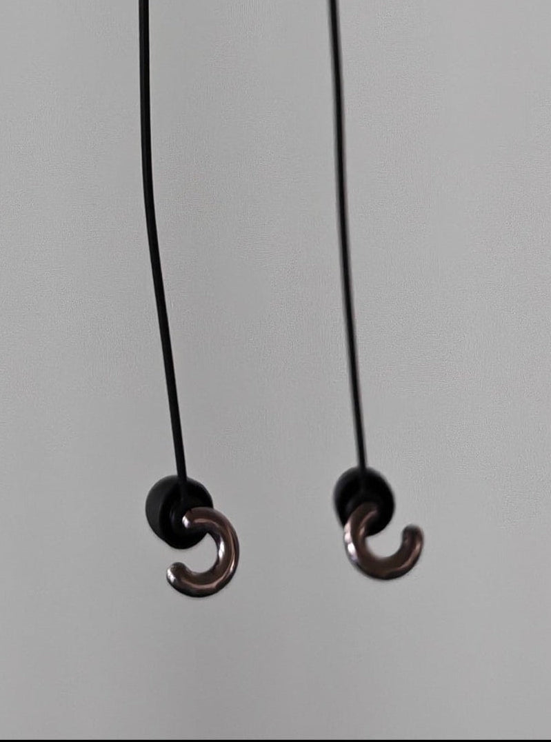 Black cord with two small round black beads held by a hand on a light gray background